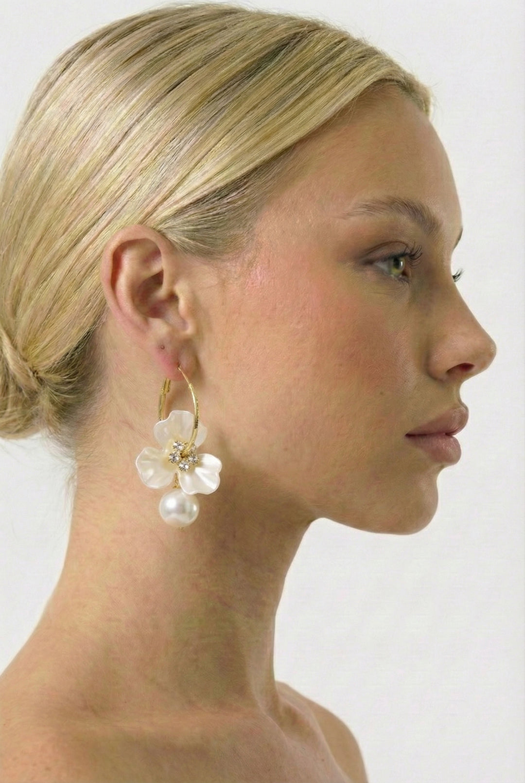 Woman wearing floral hoop earrings with a plain background