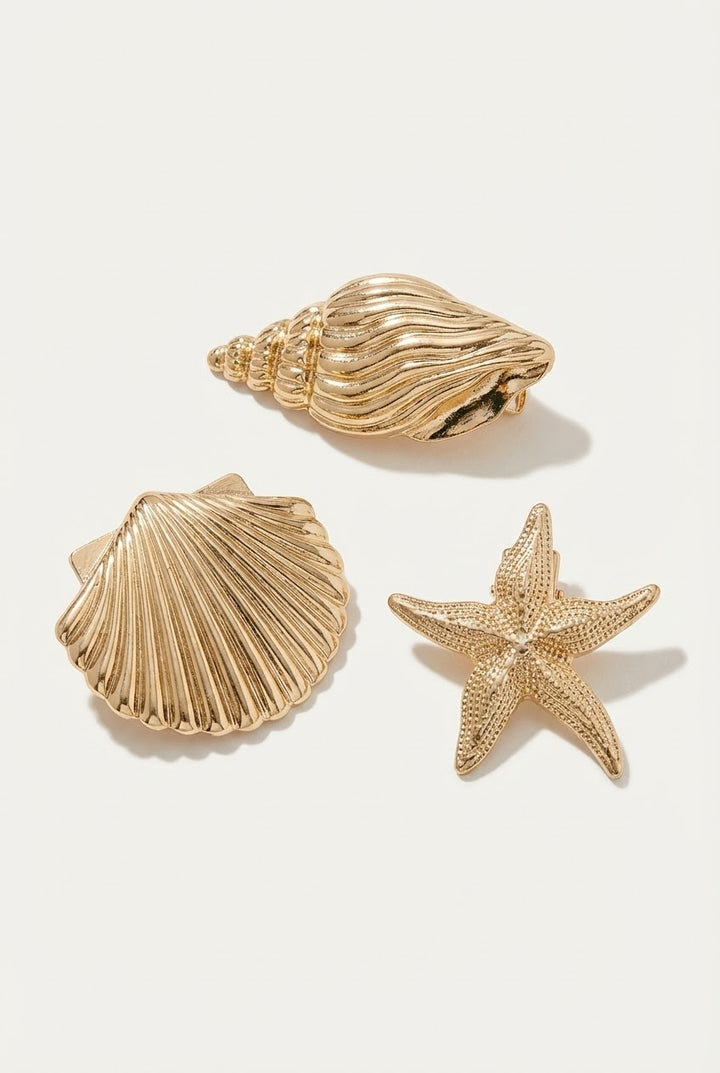 Three gold shell and starfish decorations on a white background